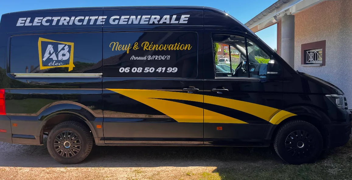Camion noir et jaune AB ELEC stationné devant une maison