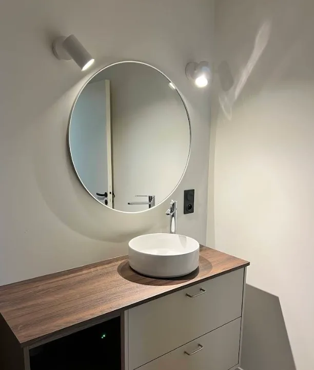 Salle de bain avec miroir rond rétroéclairé et appliques murales